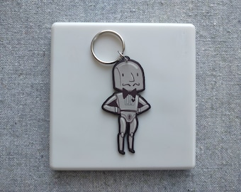 May include: A silver robot keychain with a bow tie and a small heart on its chest. The robot is standing with its arms crossed and has a slightly grumpy expression.