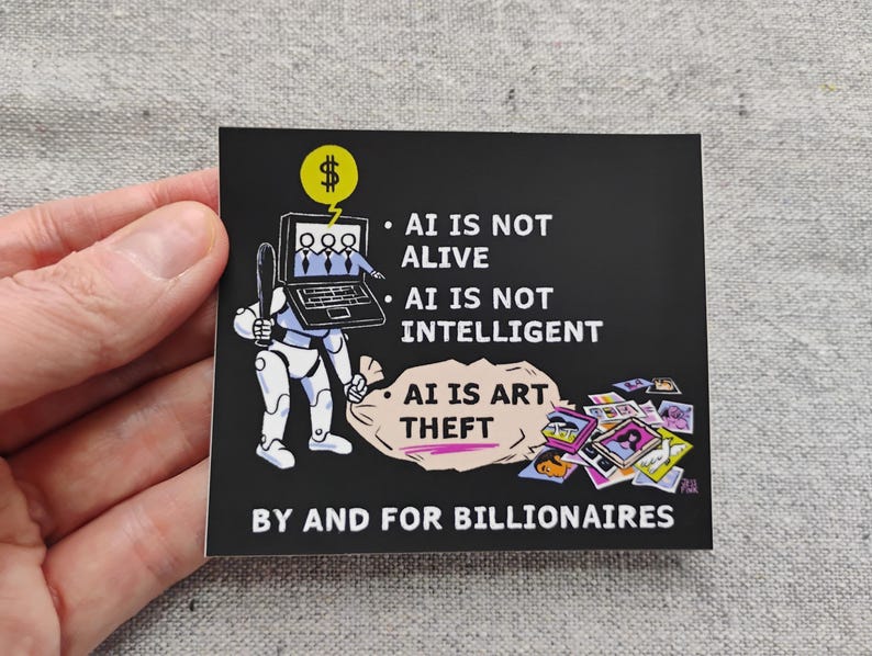 Op de afbeelding: Een zwarte vierkante sticker met witte tekst en een cartoonillustratie. De illustratie toont een robot met een laptop en een geldbuidel. De tekst luidt: "AI IS NOT ALIVE, AI IS NOT INTELLIGENT, AI IS ART THEFT BY AND FOR BILLIONAIRES."