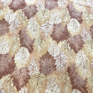 May include: A fabric with a repeating pattern of stylized leaves in shades of brown, beige, and off-white. The leaves have detailed veining, creating a textured appearance. The overall design has a natural, autumnal feel.