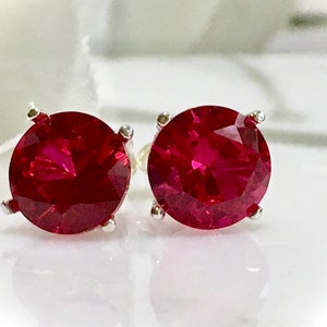 May include: A pair of silver stud earrings with round, red gemstones.
