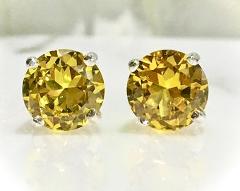 May include: A pair of silver stud earrings with round, yellow gemstones.