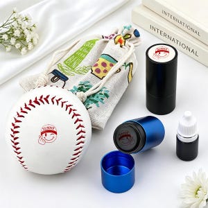 May include: A white baseball with red stitching and a red "SUNNY" smiley face icon, a beige drawstring pouch with colorful illustrations, a black cylindrical stamp case, a blue cylindrical stamp case with a lid, and a small black ink bottle.