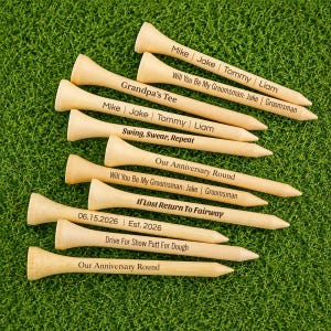 May include: A collection of light-colored wooden golf tees, each featuring custom black text engravings. Phrases include "Mike | Jake | Tommy | Liam", "Will You Be My Groomsman", "Grandpa's Tee", "Swing, Swear, Repeat", "Our Anniversary Round", and "If Lost Return To Fairway".