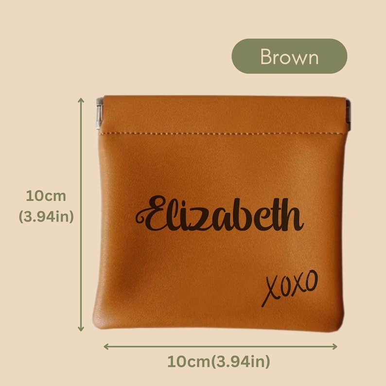May include: A brown leather pouch with a zipper closure. The pouch is 10 cm wide and 10 cm tall. It has the name "Elizabeth" and "XOXO" written on it in black.