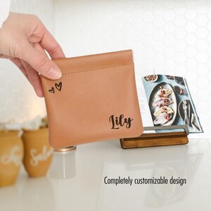 May include: A brown leather pouch with a zip closure. The pouch is personalised with the name "Lily" and two small hearts.