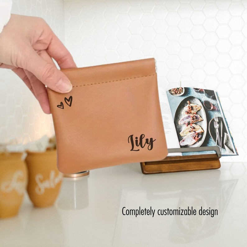 May include: A brown leather pouch with a zip closure. The pouch is personalised with the name "Lily" and two small hearts.
