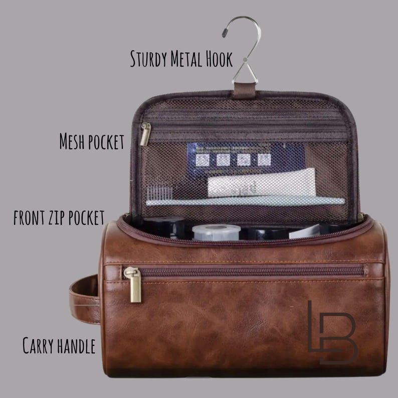 May include: A brown leather-effect travel bag with a sturdy metal hook, mesh pocket, and front zip pocket. The bag has a carry handle and a gold-coloured zip. The bag is open, revealing toiletries inside.