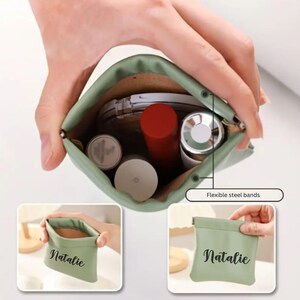 May include: A green zippered pouch with the name "Natalie" printed on it. The pouch is open and shows a variety of items inside, including makeup and a small mirror. The pouch has flexible steel bands on the sides.