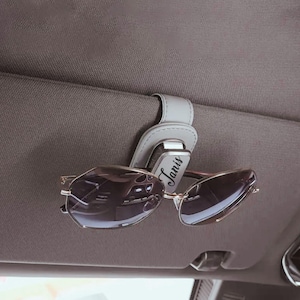 Close-up of custom engraved glasses case clipped to car visor, functional and stylish accessory for daily use.