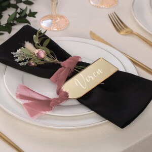 Modern acrylic name card on a gala table set with silver flatware, linen napkin, and blush floral centerpiece, perfect for use as a seating card, guest name sign, or personalized wedding favor for upscale events.