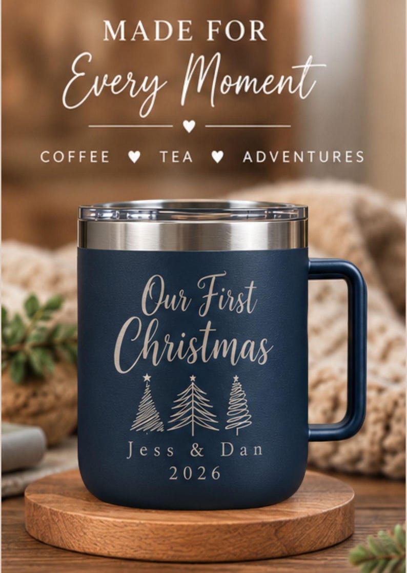 May include: A dark blue insulated mug with a silver rim and handle, featuring the text "MADE FOR Every Moment COFFEE &hearts; TEA &hearts; ADVENTURES" and "Our First Christmas" above three line-art Christmas trees, "Jess & Dan", and "2026".