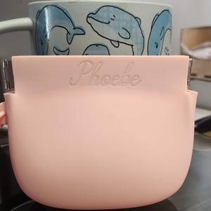 K&ouml;nnte beinhalten: Eine wei&szlig;e Keramik-Tasse mit schwarzem Henkel und dem Text "But First, Coffee" in handschriftlichem Stil. Die Tasse steht auf einer wei&szlig;en Oberfl&auml;che. Die Tasse ist etwa 10 cm hoch.