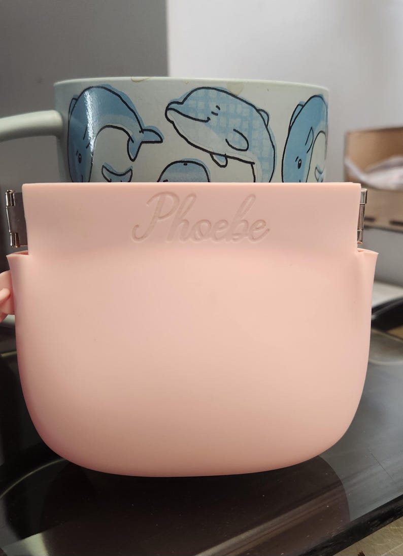 K&ouml;nnte beinhalten: Eine wei&szlig;e Keramik-Tasse mit schwarzem Henkel und dem Text "But First, Coffee" in handschriftlichem Stil. Die Tasse steht auf einer wei&szlig;en Oberfl&auml;che. Die Tasse ist etwa 10 cm hoch.