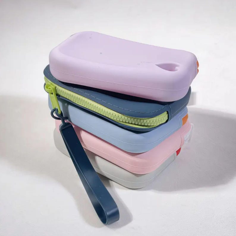 May include: A stack of five silicone pouches in various colors, including light purple, blue, pink, and gray. The pouches have a zipper closure and a strap.