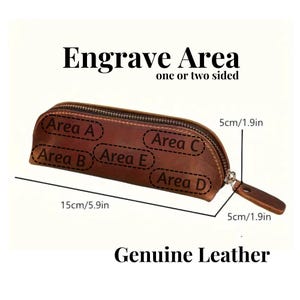 Puede incluir: Un estuche de l&aacute;pices de cuero marr&oacute;n con cierre de cremallera. Se muestra el texto "Engrave Area" y "Genuine Leather". El estuche mide 15 cm de largo y 5 cm de ancho. La imagen muestra &aacute;reas para grabar.