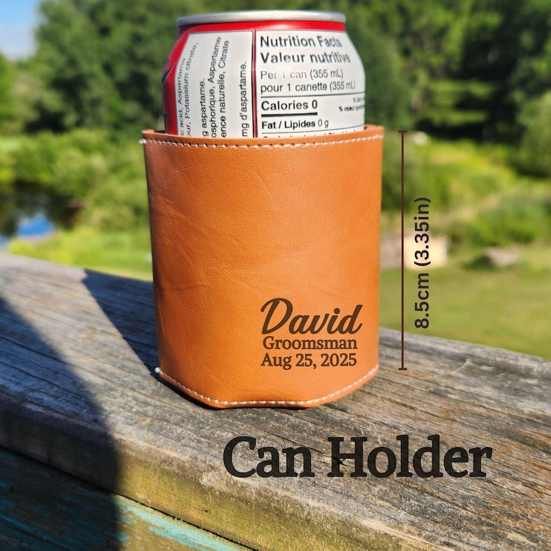 May include: A tan leather can holder with the name "David", the word "Groomsman", and the date "Aug 25, 2025" printed on the front. The can holder is 8.5cm tall and holds a can of soda.