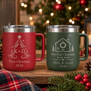 May include: A red and a green stainless steel mug with silver rims and handles. The red mug features a white Christmas tree graphic with the text K + D, First Christmas, 2026. The green mug shows a house graphic with the text Our First Christmas in our home, Mike & Sarah, 2026.