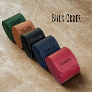 May include: A row of five leather watch cases in various colors: green, tan, black, navy, and red. Each case is personalized with a name in a contrasting color. The text "BULK ORDER" is in the background.