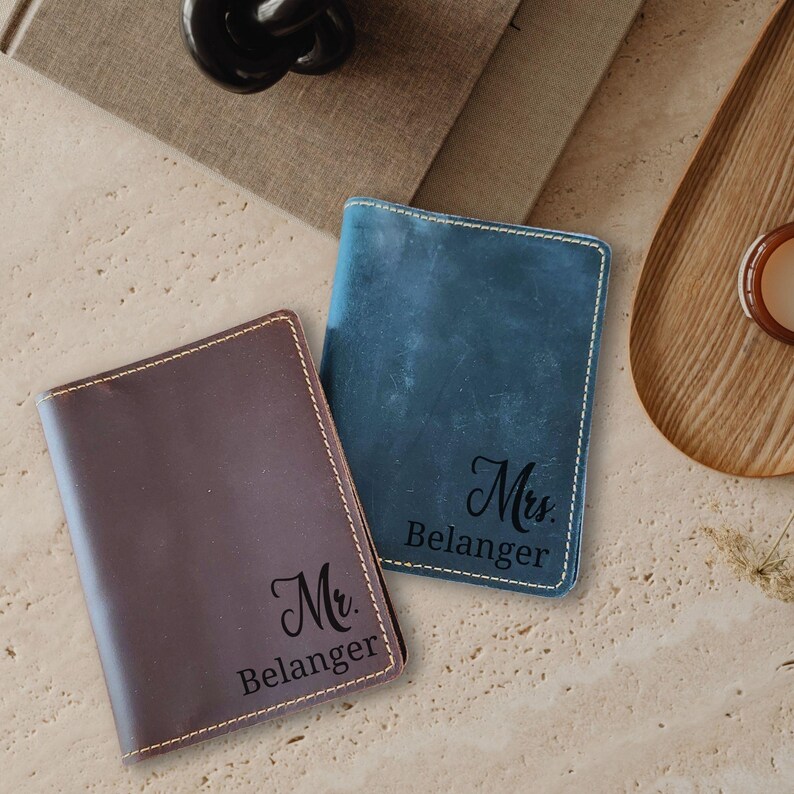 Flatlay of blue and brown leather engraved passport wallet tag on a table surface, styled as a premium travel gift set for men or women.