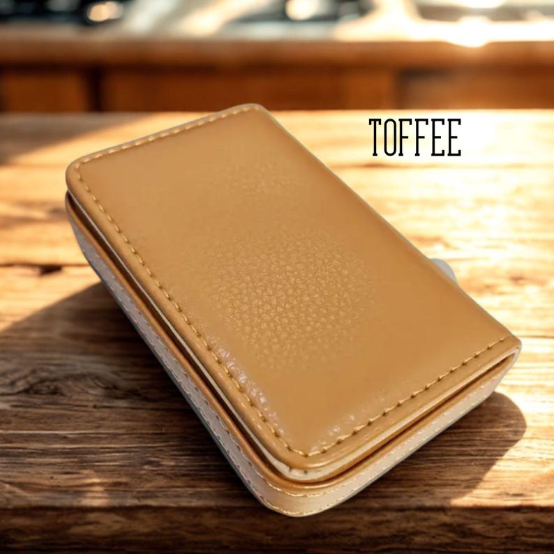 May include: A rectangular, toffee-colored leather case with a textured surface and stitched edges. The case has a light beige border and the word "TOFFEE" is printed in black.