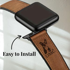 Pu&ograve; includere: Un cinturino per orologio in pelle marrone con un quadrante nero. Il cinturino presenta una silhouette di cane e le lettere "DMC". Il testo "Easy to Install" &egrave; anche visibile.