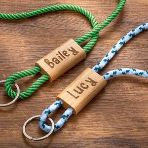 Pode incluir: Dois chaveiros de madeira personalizados com cord&otilde;es de corda. O chaveiro &agrave; esquerda tem um cord&atilde;o de corda verde e preto e diz "Bailey" na etiqueta de madeira. O chaveiro &agrave; direita tem um cord&atilde;o de corda azul e branco e diz "Lucy" na etiqueta de madeira.