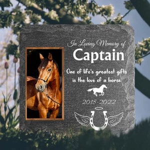 Pu&ograve; includere: Una pietra commemorativa in ardesia grigia con una foto di un cavallo marrone. La pietra ha il testo "In Loving Memory of Captain" e "One of life's greatest gifts is the love of a horse". Le date "2018-2022" sono anche sulla pietra.