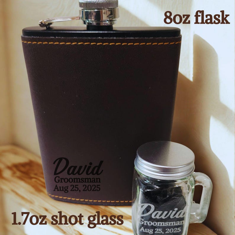 May include: A dark brown 237ml flask with a silver cap and a 50ml shot glass. The flask and shot glass are personalized with the name "David" and the text "Groomsman Aug 25, 2025". The flask has gold stitching.