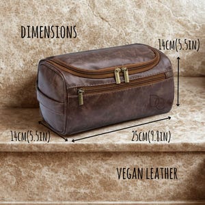 May include: A brown vegan leather wash bag with gold zips. The bag is rectangular, measuring 25cm long and 14cm high and wide. The image includes the text "Dimensions" and "Vegan Leather".
