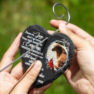 Puede incluir: Memorial de pizarra negra en forma de coraz&oacute;n con una foto de un perro y el texto "Those we Love don't go away They walk beside us Every day UNSEEN UNHEARD but always near Still loved still AND" con una estaca de metal.