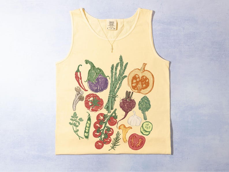 May include: A pale yellow vest top with a colourful print of vegetables such as aubergine, tomatoes, and asparagus. The design has a hand-drawn style, suitable for a farmer's market or anyone who enjoys gardening. The print includes a pumpkin.