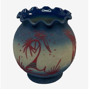 May include: A blue and white ceramic vase with a scalloped rim. The vase is decorated with a red and white design of stylized trees and flowers.