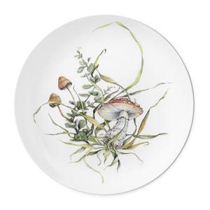 May include: A white ceramic plate with a watercolor illustration of a red and white mushroom with green leaves and stems.