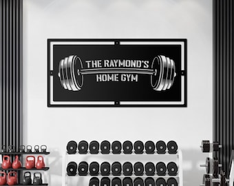 May include: Black metal sign with a barbell and the text "The Raymond's Home Gym". The sign is mounted on a white wall above a set of black dumbbells on a white metal rack.