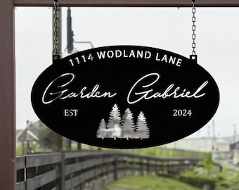 May include: Black oval metal sign with white text that reads "1114 Woodland Lane Garden Gabriel Est 2024". The sign has a silhouette of three pine trees in the center.