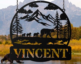 May include: Black metal sign with a mountain scene and a family of bears. The sign is round and has the name "VINCENT" on the bottom.