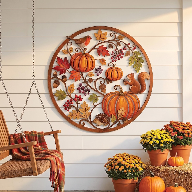 May include: A circular metal wall art piece featuring a relief design of orange pumpkins, red and green autumn leaves, purple berries, a brown squirrel, a small hedgehog, and a robin bird, all enclosed within a thin brown circular frame.