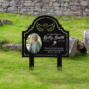 Könnte beinhalten: Schwarzes Metall-Gedenkschild mit einem Foto einer Frau, Engelsflügeln und dem Text "In Loving Memory of Betty Smith Sep.15.1966 Mar.23.2024 Those we love don't go away They walk beside us everyday Forever Loved"