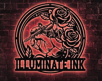 May include: A black metal sign with a red neon glow, featuring a hand holding a tattoo machine, surrounded by roses and leaves. The text "ILLUMINATE INK" is displayed at the bottom, set against a brick wall background.