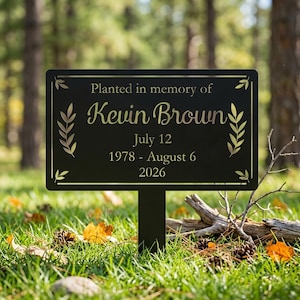 Peut inclure: Un piquet de jardin commémoratif rectangulaire en métal noir avec une gravure dorée indiquant : Planted in memory of Kevin Brown, July 12, 1978 - August 6, 2026. Le panneau est orné de motifs de branches dorées sur les côtés gauche et droit.