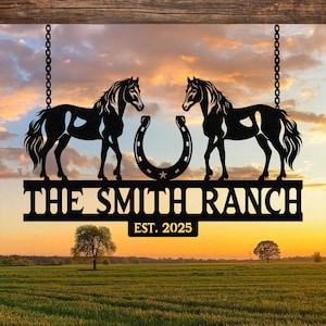 Puede incluir: Letrero de metal negro con dos siluetas de caballos enfrentados, una herradura y el texto "THE SMITH RANCH EST. 2025". El letrero cuelga de cadenas contra un atardecer sobre un campo.