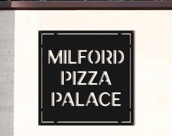 Pode incluir: Placa de metal preta com as palavras "MILFORD PIZZA PALACE" recortadas em branco. A placa é quadrada com uma fina borda branca e está montada em uma parede branca.