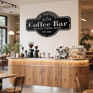 Peut inclure: Un panneau métallique noir avec l'inscription "The Johnsons Coffee Bar", le texte "Open Daily Freshly Brewed" et "Est. 2025". Le panneau est au-dessus d'un bar à café avec des machines à café, des moulins et des pâtisseries.