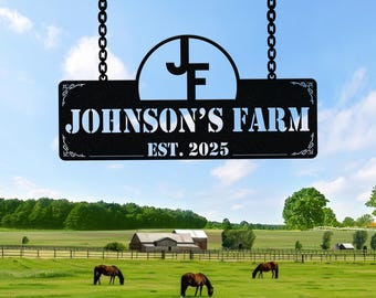 Puede incluir: Letrero metálico negro con el texto "JOHNSON'S FARM EST. 2025" colgado de cadenas. El letrero presenta las iniciales "JF" dentro de un semicírculo. El fondo muestra caballos pastando en un campo verde.