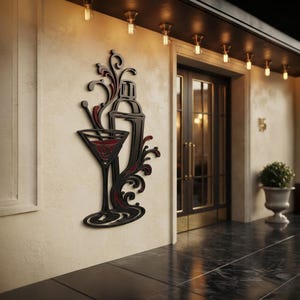 May include: A black wall-mounted decorative sign featuring a stylized cocktail shaker and a martini glass with swirling liquid accents in deep red. The design is composed of layered cutouts creating a dimensional silhouette against the wall.