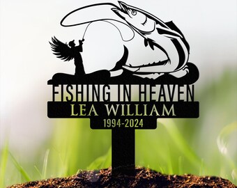 May include: Black metal memorial garden stake with a silhouette of an angel fishing a large fish. The stake has the text "Fishing in Heaven" and "Lea William 1994-2024".