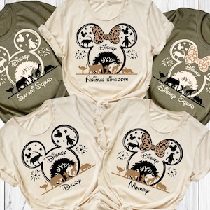 May include: Five short-sleeved t-shirts in olive green and cream colors. Each shirt features a Mickey Mouse head design with animal silhouettes, a tree, and the word "Disney". Some shirts say "Safari Squad", "Animal Kingdom", "Daddy", and "Mommy".