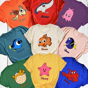 May include: A collection of colorful t-shirts featuring cartoon sea creatures. Each shirt has a different character with a family-related title, such as "Grandma", "Sister", and "Mommy". The shirts are in various colors, including orange, red, purple, and blue.