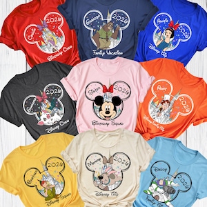 Puede incluir: Una colecci&oacute;n de camisetas coloridas con dise&ntilde;os tem&aacute;ticos de Disney. Cada camiseta tiene un contorno de cabeza de Mickey Mouse con personajes y texto como "Cousin", "Grandpa", "Sister" y "Daddy", junto con el a&ntilde;o "2026".