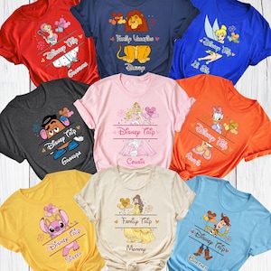 K&ouml;nnte beinhalten: Eine Auswahl an farbenfrohen T-Shirts mit Disney-Charakteren. Jedes Shirt zeigt einen anderen Charakter und die Aufschrift "Disney Trip" sowie eine Familienrolle wie "Opa", "Cousin" oder "Schwester". Die Shirts sind in verschiedenen Farben erh&auml;ltlich, darunter Rot, Blau und Gelb.